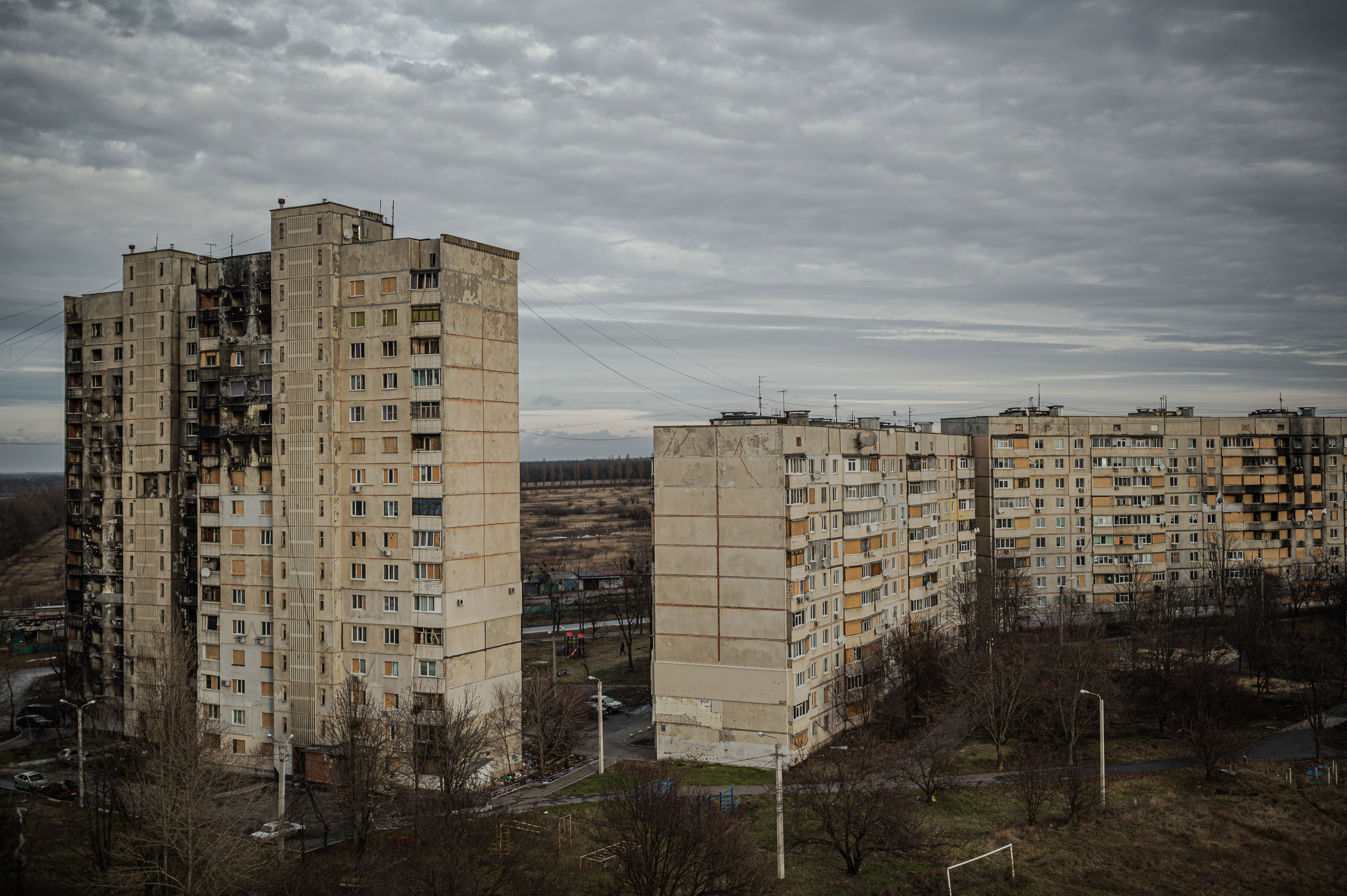 The northern district of Saltivka, the largest and most densely populated part of Kharkiv: a monolith of grey concrete high-rises. Beyond them, a line of garages; beyond the garages, open fields. ©Denis Vėjas