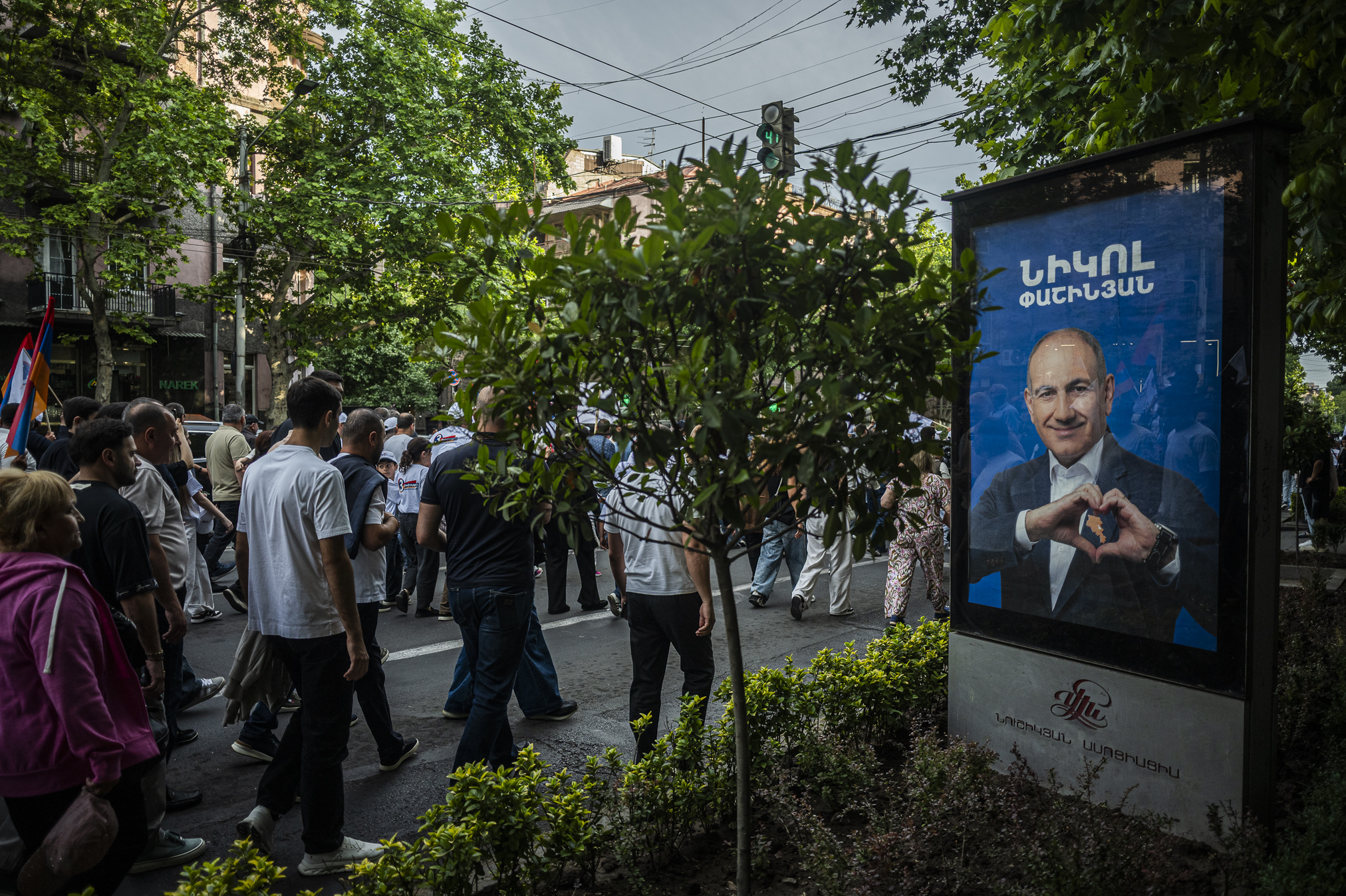 Participants in a Strong Armenia rally walk past an election poster of Prime Minister, Nikol Pashinyan. Immediately after the 2018 Revolution, Pashinyan enjoyed the support of 80–90 percent of voters. He remains the most popular politician, but his support now stands at only 10–20 percent. More than 60 percent of Armenians trust no politician at all. © Denis Vėjas