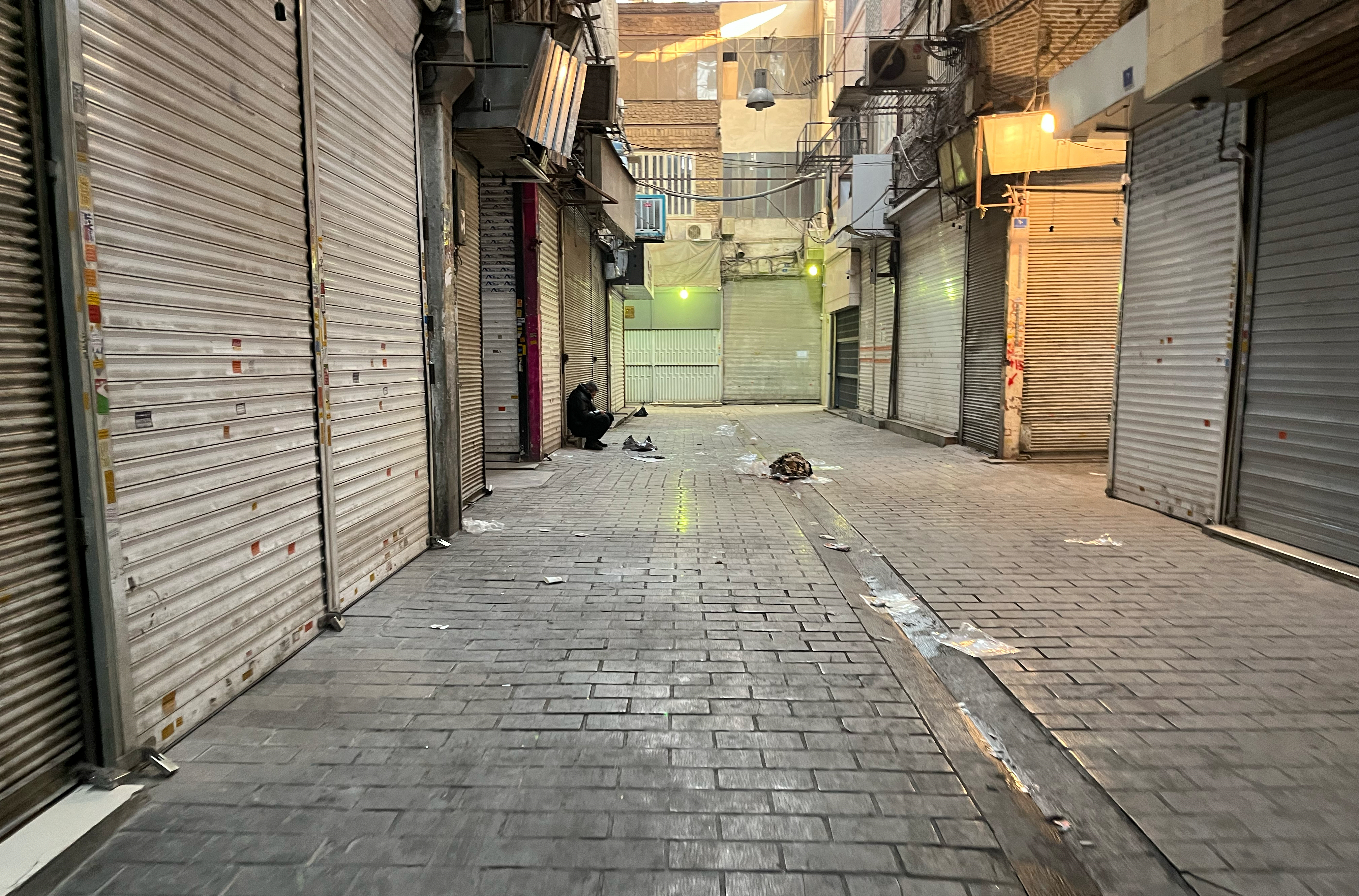A man sits as shops are closed during protests in Tehran's centuries-old main bazaar, Iran, Tuesday, January 6, 2026. ©AP Photo/Vahid Salemi