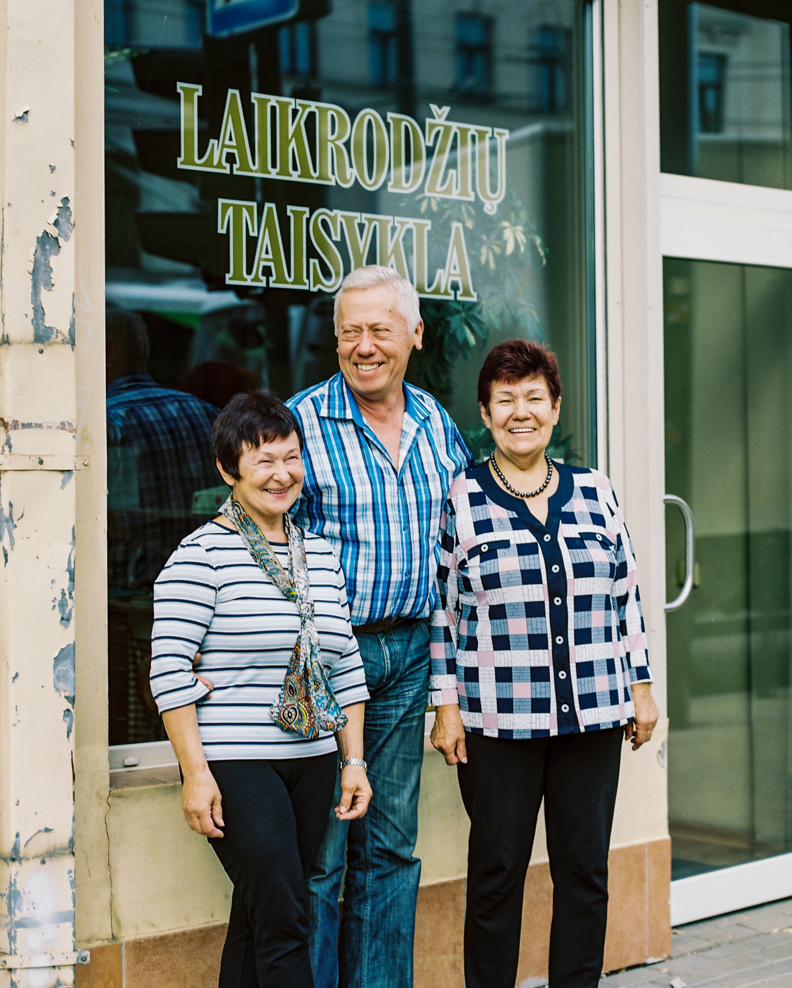 Laikrodininkai Irena, Jonas ir Raisa prie savo seniausios laikrodžių taisyklos Kaune. Iš videopasakojimo „Laikrodžių gydytojai“. ©Berta Tilmantaitė