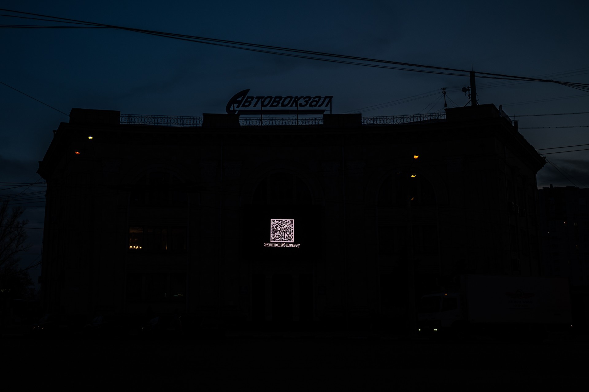 Naktinis Charkivas. Ant autobuso stoties pastato šviečia QR kodas, vedantis į anketą užsirašyti į kariuomenę. ©Denis Vėjas