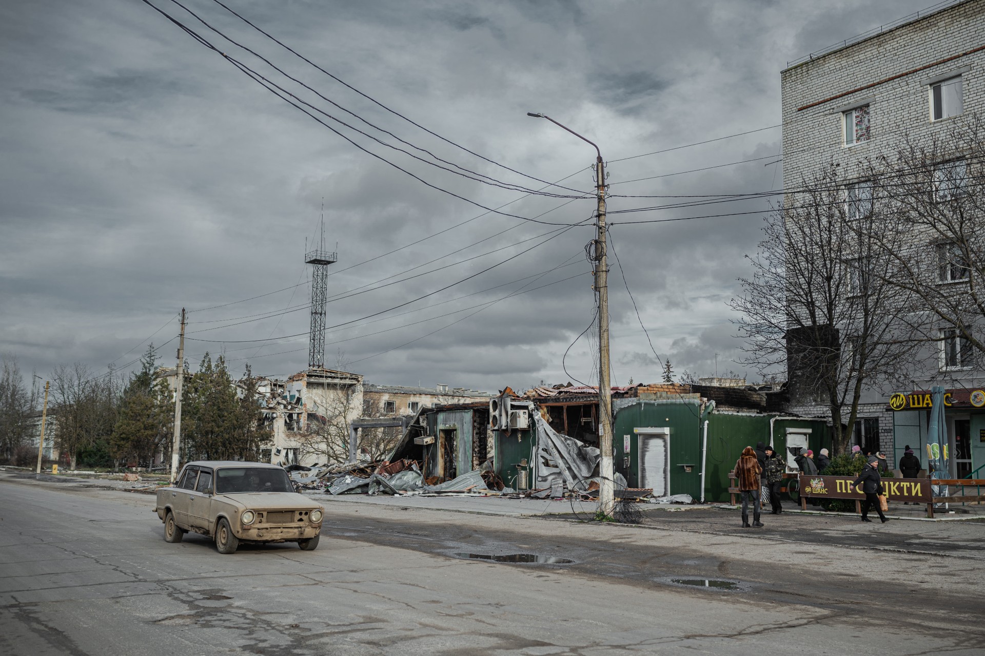 Gyventojai laukia eilėje prie humanitarinės pagalbos išdavimo punkto šalia susprogdintos turgavietės Snihurivkoje.