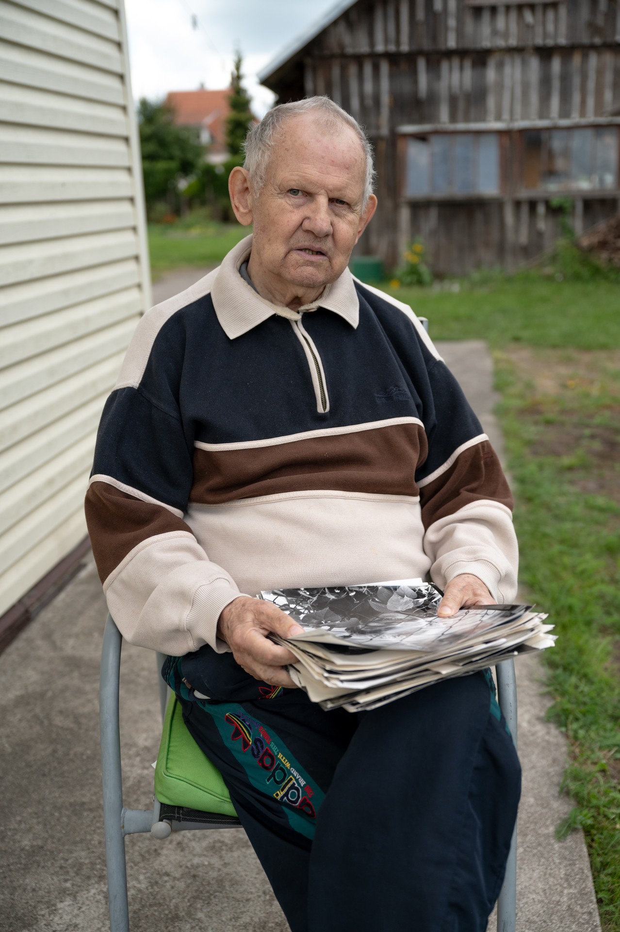 Benjamino portretas namų kieme. Rankose pluoštas jo darytų nuotraukų. ©Mindaugas Černeckas