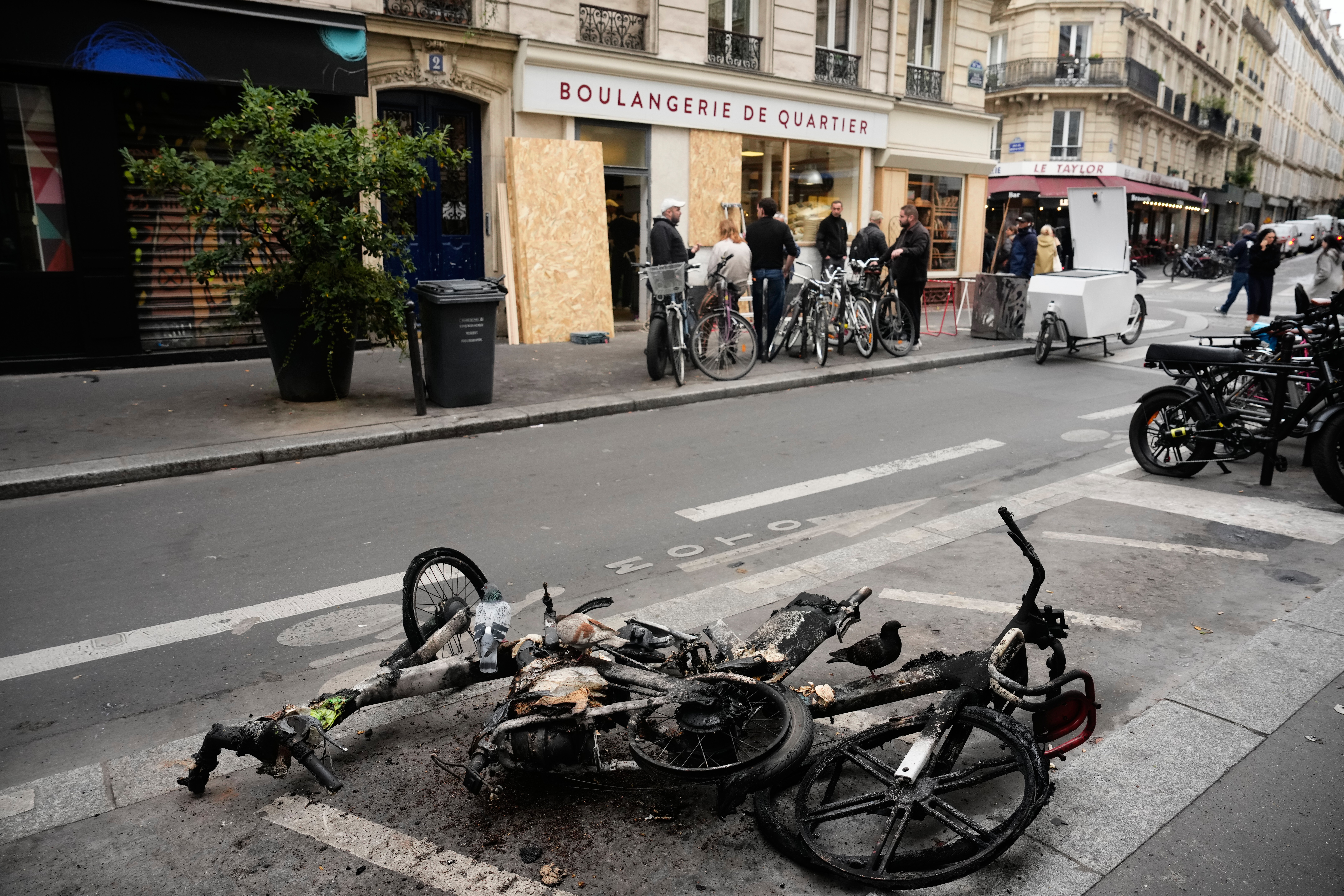 Sudegę elektriniai dviračiai guli ant kelio netoli kepyklos po to, kai spalio 17-18 d. savaitgalį Prancūzijoje vykę protestai peraugo į riaušes ir plėšikavimus. Paryžius, spalio 21 d. ©Teresa Suarez / AP Photo