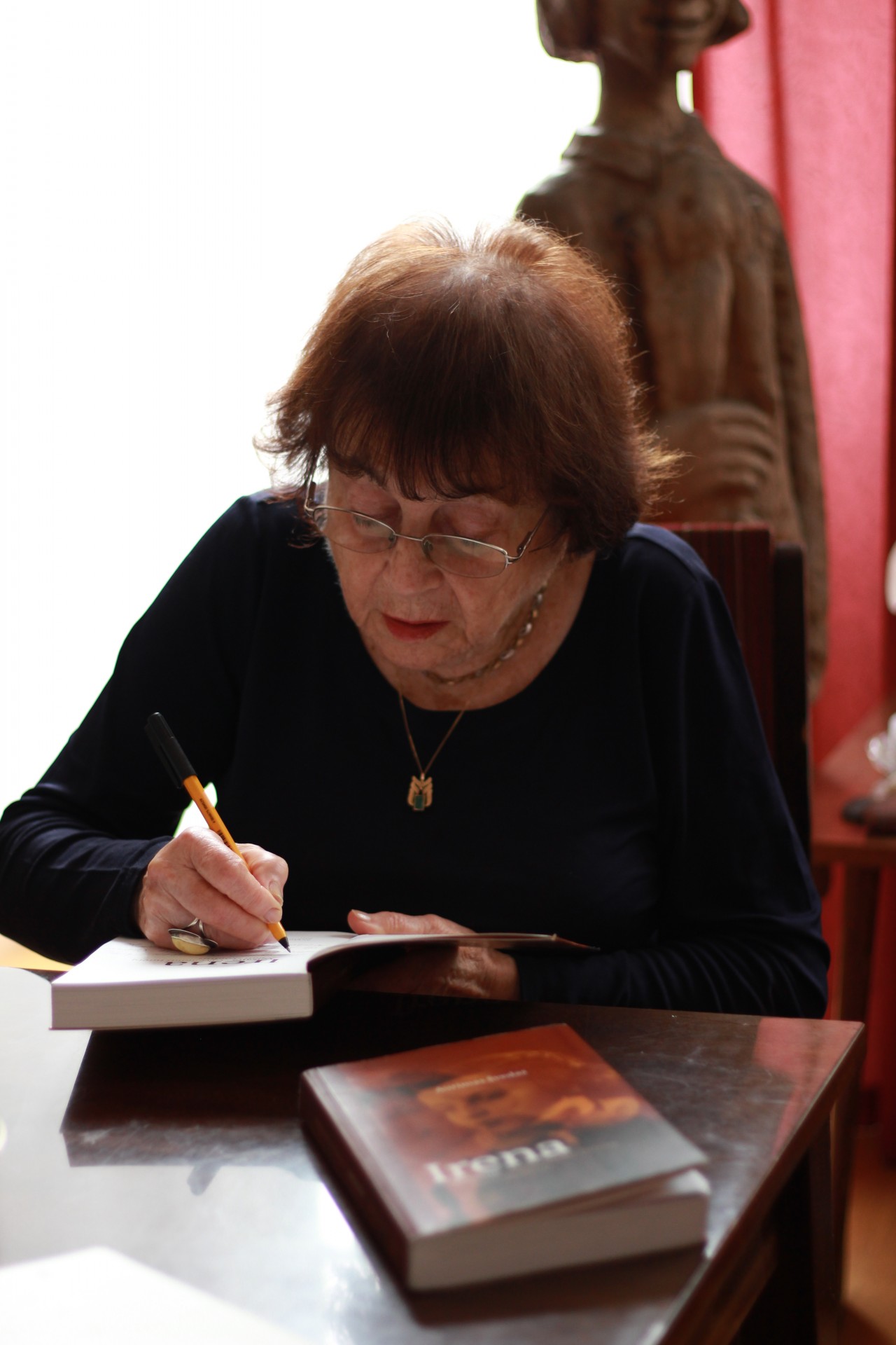 Irena Veisaitė pasirašo istoriko Aurimo Švedo knygą „Gyvenimas turėtų būti skaidrus“. Joje Švedas kalbina profesorę apie jos gyvenimą. ©Gintarė Kulytė