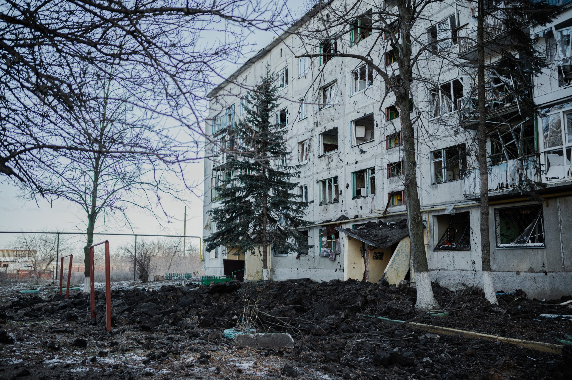Paaiškėja, kad artilerija pataikė į kaimynų namo kiemą, esantį už maždaug 500 metrų. Viena laiptinė sugriauta, visi namo langai išmušti sprogimo bangos, kieme paliktas gilus krateris. ©Denis Vėjas