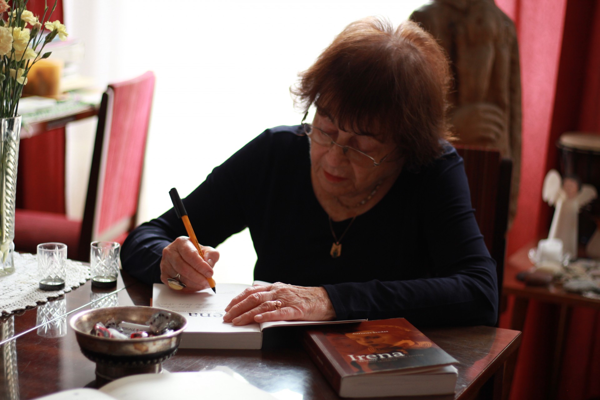 Irena Veisaitė pasirašo istoriko Aurimo Švedo knygą „Gyvenimas turėtų būti skaidrus“, kurioje autorius kalbina profesorę apie jos gyvenimą. ©Gintarė Kulytė