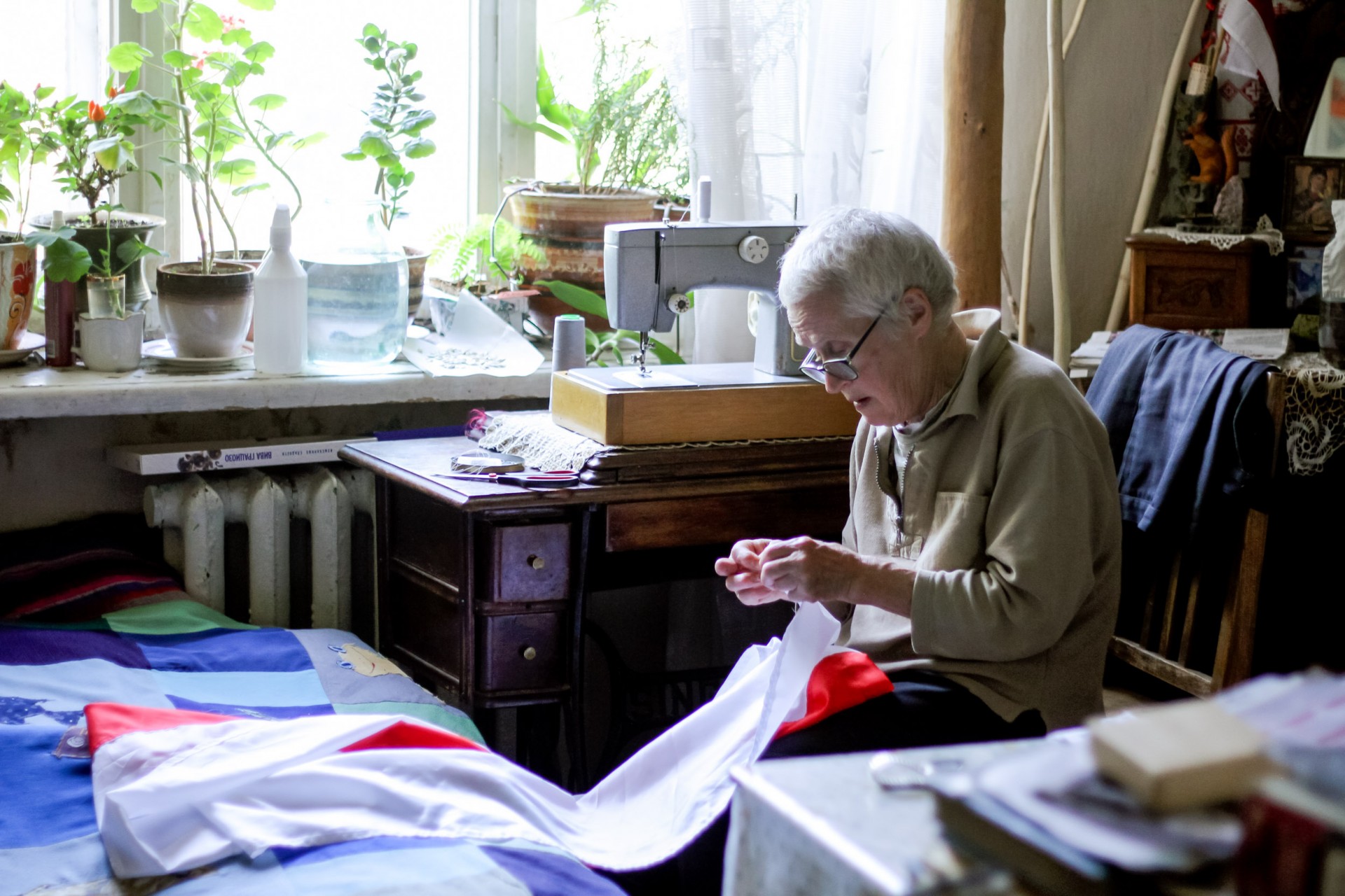Nina Baginskaja siuva baltai raudoną Baltarusijos vėliavą namuose. ©Marta Klinava