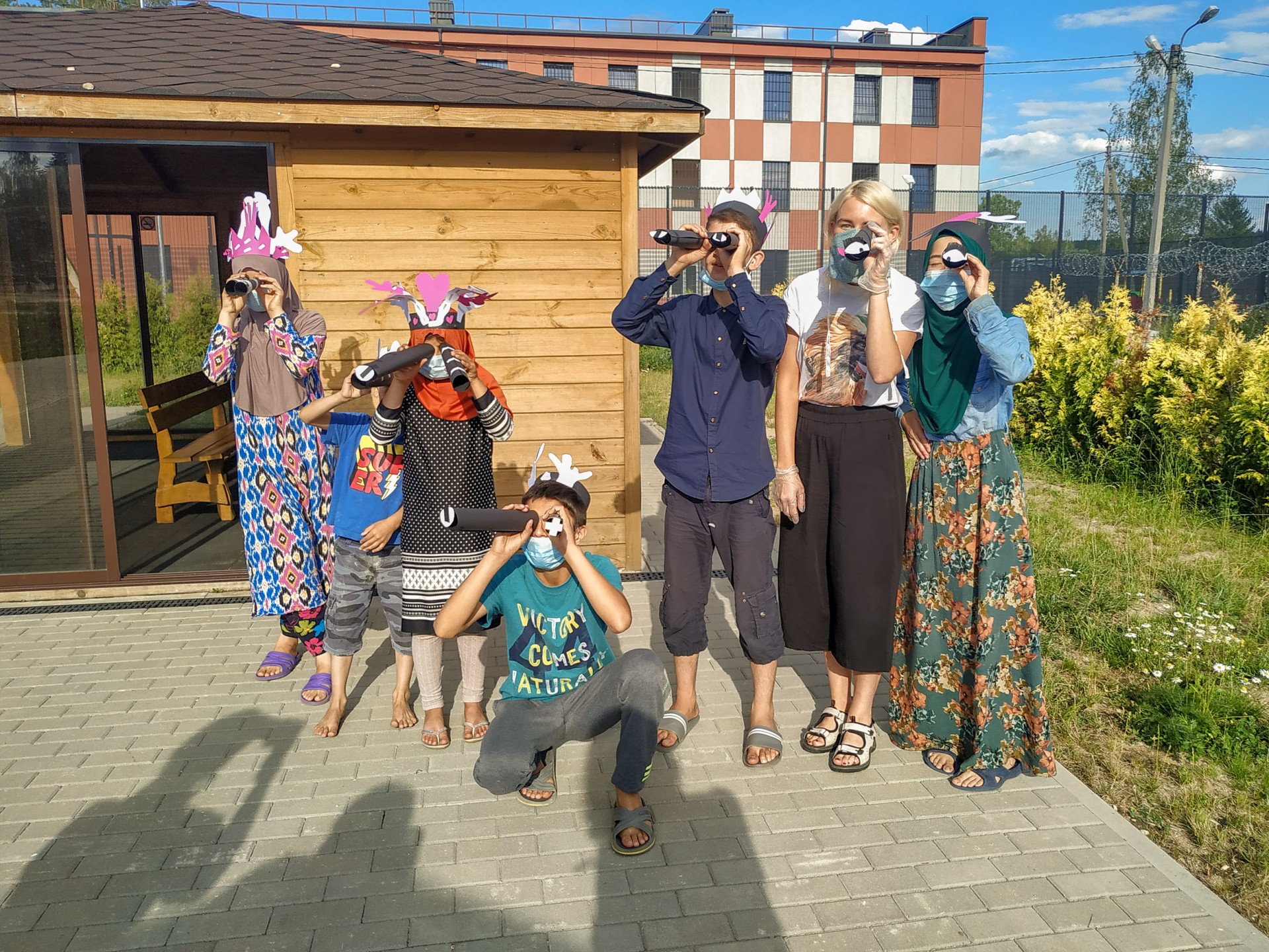 Pabradės užsieniečių registracijos centro vaikai pozuoja su savo rankdarbiais iš popieriaus. 2020-ųjų vasara. ©Martyna Šulskutė