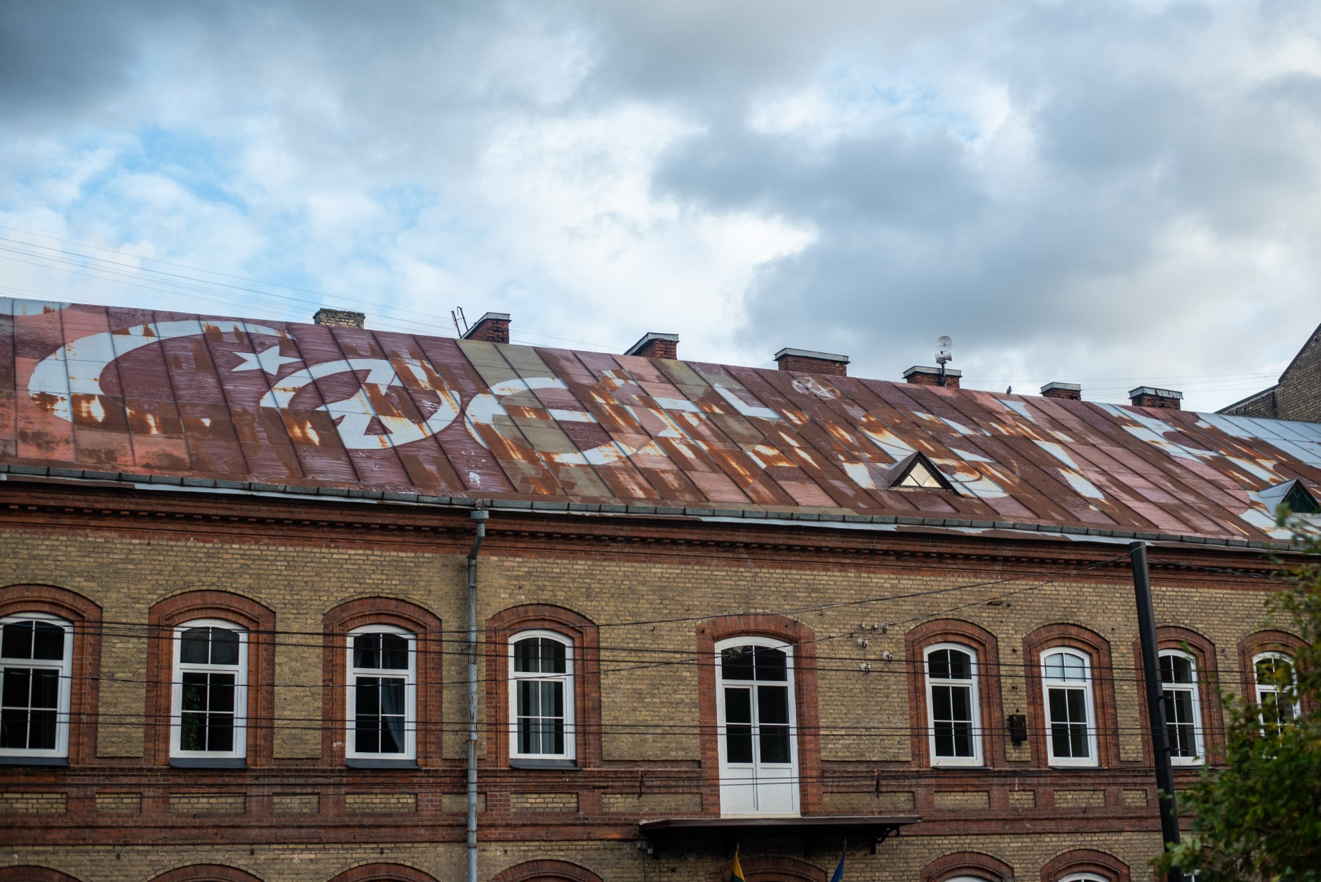 „Coexist“ – „Sugyvenkim“. Užrašas ant namo stogo Vilniaus centre. ©Berta Tilmantaitė
