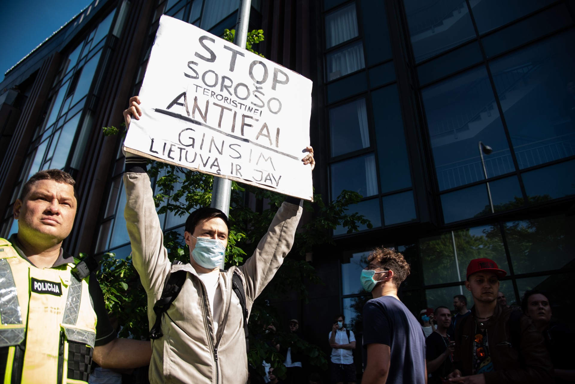 Dalyvius pasitikęs Kęstutis Juozapas Tamašauskas prie kaltinimų Soros’ui prijungė ir ANTIFA – pasaulinį anti-fašistinį judėjimą, kurį Donaldas Trumpas Tviteryje paskelbė teroristiniu. Kita vyro plakato pusė sakė „Ginsim Lietuvą ir D. Trampą“. Anot eitynių dalyvio 17-mečio Klaido, anti-protestuotojai įžeidinėjo George Floyd atminimą ir kalbėjo per mirusiajam skirtas 8 minutes tylos. Tad jis priėjo plakatą atimti. ©Severina Venckutė