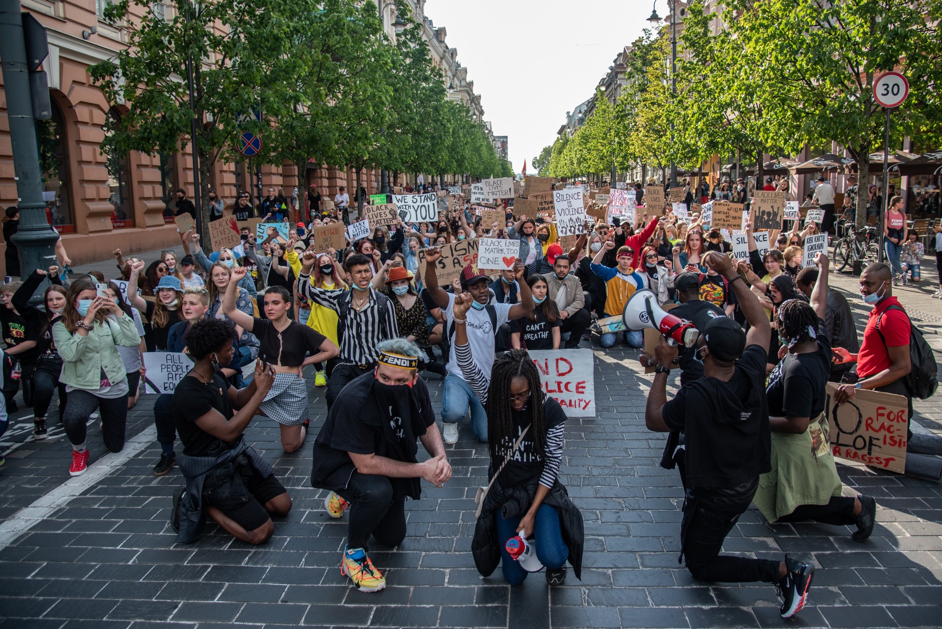 Protestuotojai klūpi Gedimino prospekte. Klūpėjimas ant vieno kelio tapo pasaulinių „Black Lives Matter“ protestų simboliu. Tylos minute taip pagerbiami nuo policijos mirę juodaodžiai žmonės. Anot praėjusių metų tyrimo, vidutiniškai 1 iš 1,000 juodų vyrų JAV rizikuoja būti nušautas policijos. ©Severina Venckutė