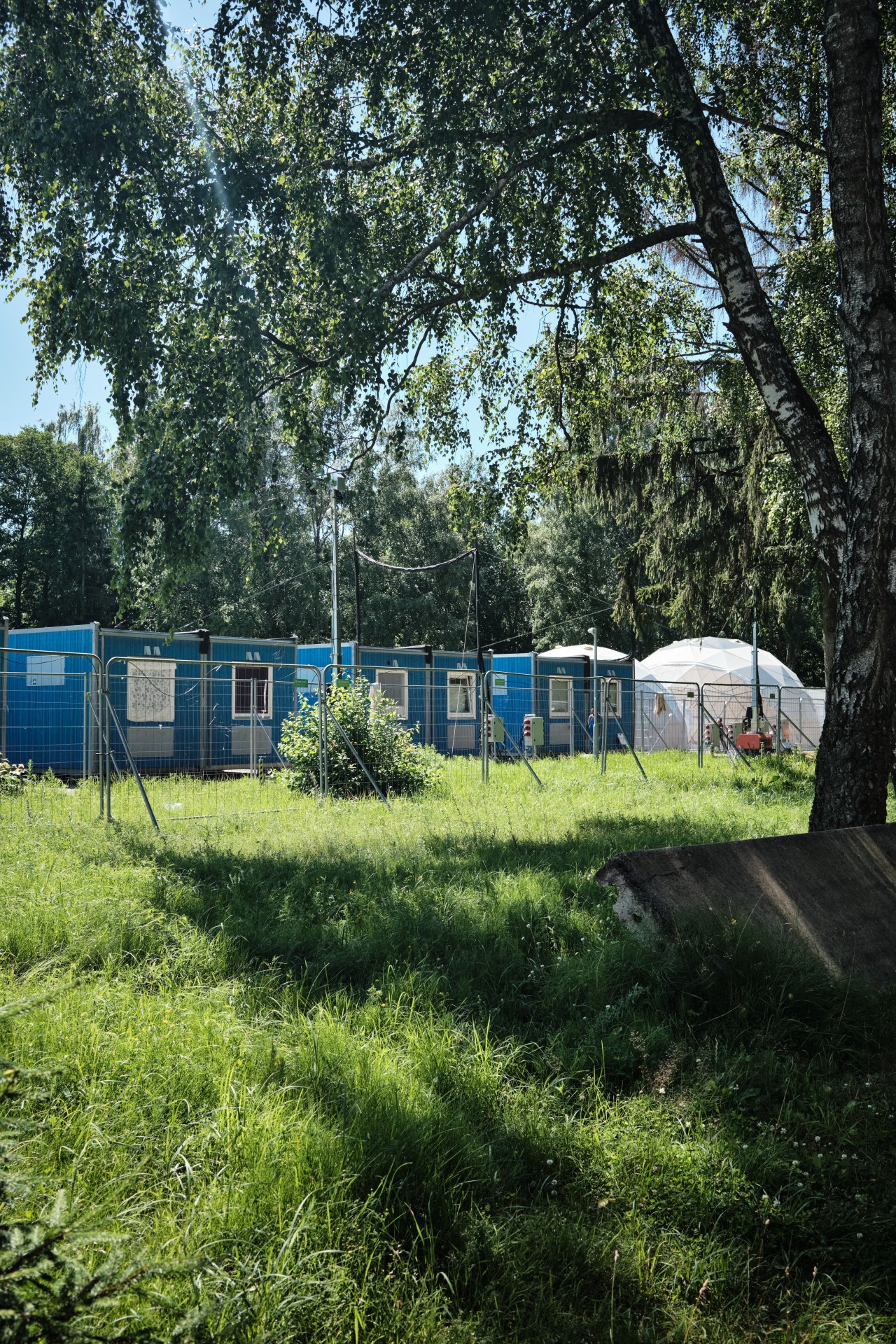 Prieglobsčio prašytojų gyvenvietė Rukloje, 2022-ųjų liepa. Rukloje gyvena ir prieglobstį gavę, ir prašantys asmenys – bet juos skiria tvora. ©Karolis Pilypas Liutkevičius
