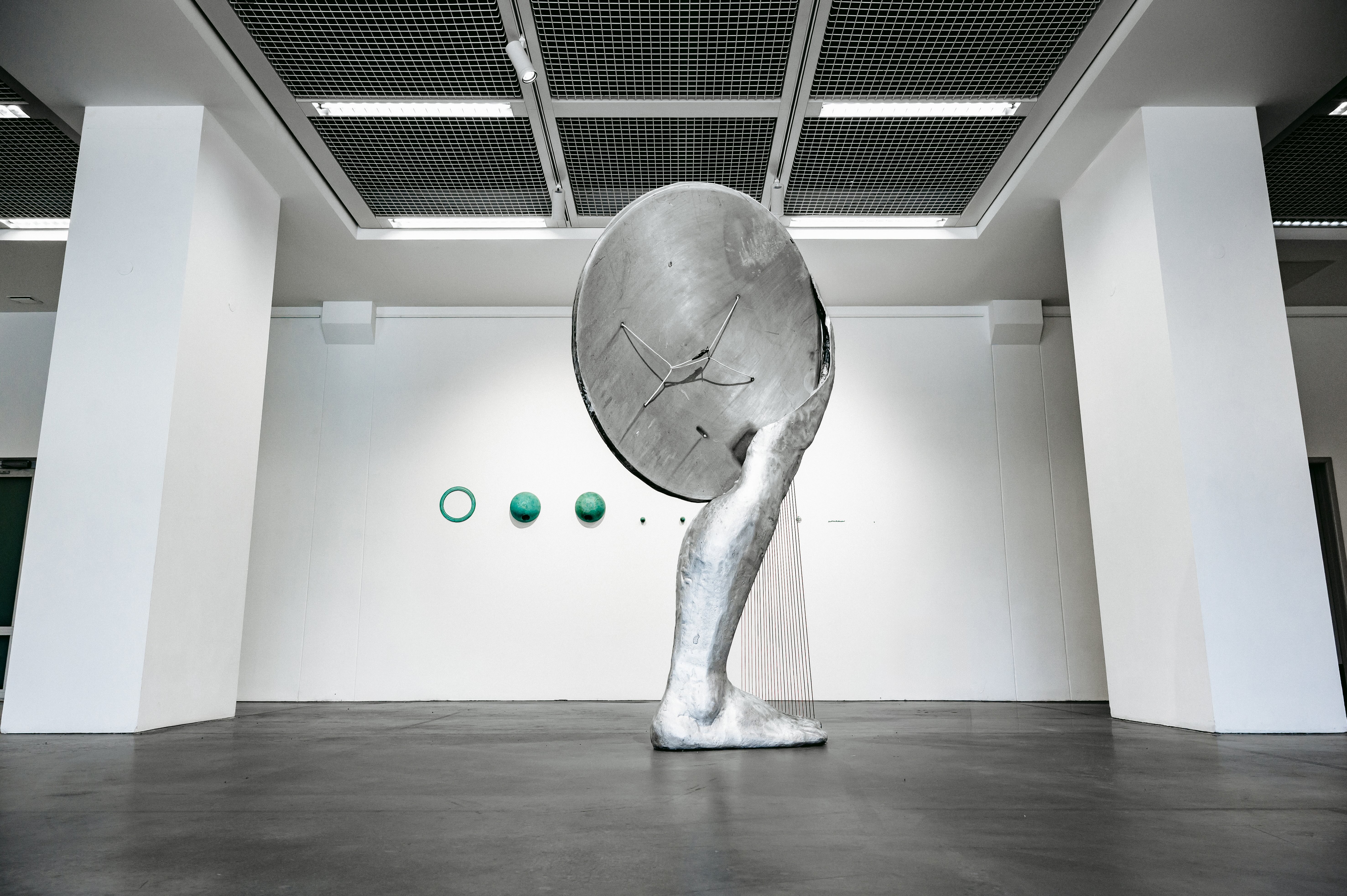 Matas Janušonis „NSO (neatpažintas stovintis objektas)“ (2025), fone –  „Vidinis vakuumas“ (2022). ©Rusnė Šimulynaitė